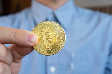 Siber uzay arka planında Bitcoin tutan bir işadamı yeni sanal para olan BTC 'yi ısırdı. Altın Bitcoin 'i tutan adam.