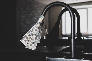 İçinden dolar akan bir musluk. Pahalı su kaynağı. Nüfus için kamu hizmetlerinin fiyatını artırma kavramı. Evde pahalı sıcak ve soğuk su var..