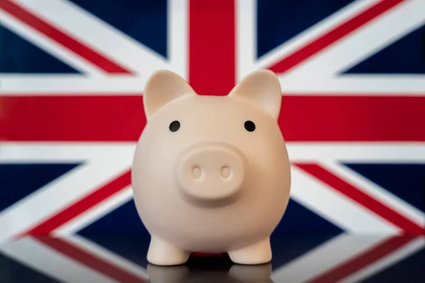 Economy of UK concept. Pink piggy bank on British flag close up. Concept of financial crisis and save money