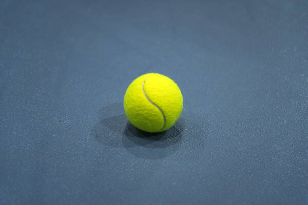 A flat lay close-up photo of the yellow tennis ball on the blue background or tennis court.