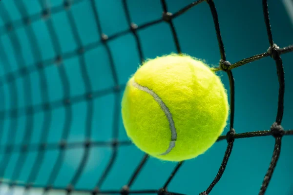 a tennis ball hit a black net on the background of a tennis court