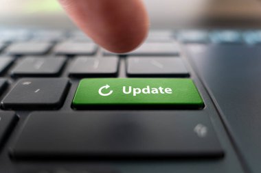 Modern siyah bilgisayar klavyesinde UPDATE sözcüğüyle yeşil düğmeye basan adam, kapat