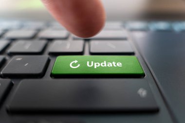 Man pressing green button with word UPDATE on modern black computer keyboard, closeup clipart