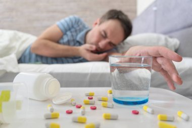 Hangover. Man take Pill and Water. Man in Bed Morning Headache. Man Using Aspirin. Glass of Water Close Up. symptom is food poisoning. clipart