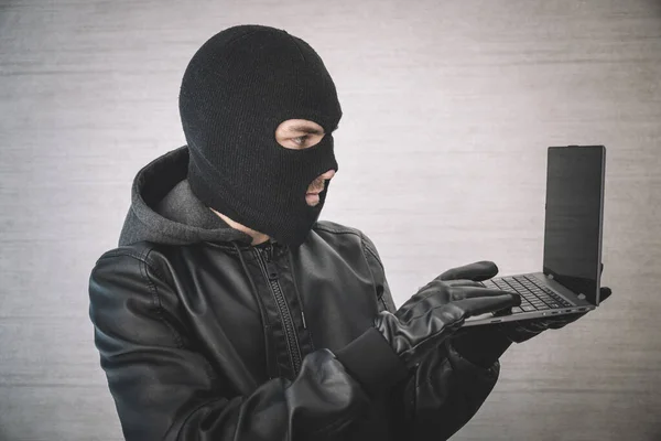 网络犯罪 精心策划的黑客和科技犯罪 男性黑客在白色房间里带着手提电脑 黑客戴着黑色面具带着现代超薄本 盗用身份资料 — 图库照片