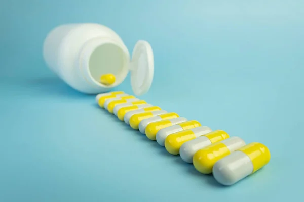 Ein Stapel Gelber Pillen Verstreut Aus Einem Weißen Plastikgefäß Auf — Stockfoto