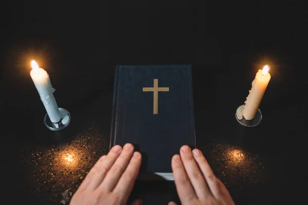Bible and three burning candles on a black table. Christian sermon. Christian faith. Protestantism, Catholicism and Orthodoxy. Faith in Jesus Christ. Study of the word of God.