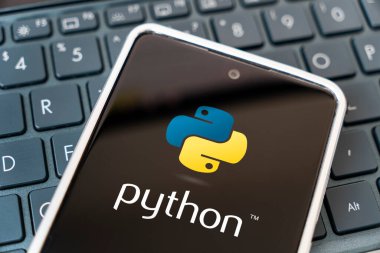 Mobil gelişim için programlama dili, konsept. Laptop klavyesinde akıllı telefon. Cep telefonu ekranında logo pitonu var. Barnaul. Rusya 28 Mart 2023.