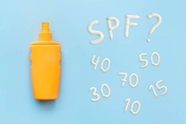 Güneş kremi, turuncu şişe, mavi arka planda güneş koruması, kopyalama alanı. Güneş yanıklarından korunmak için sprey. Güneş koruma kremi için farklı spf değerleri
