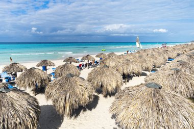 Küba, Varadero sahilinde saman şemsiyeler. Tatil ve rahatlama geçmişi. Turistler plajda güneşleniyor..