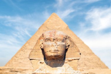 Büyük Sfenks, Giza Mısır 'daki en eski anıttır. Sfenksin başı, Chephren piramidinin arka planına karşı tamamen simetriktir. Arka plan güzel bulutlu mavi gökyüzü