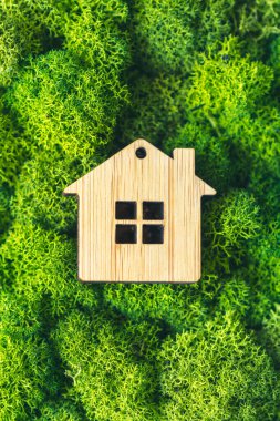 Miniature wooden house on green moss. The concept of selling, insuring or renting real estate. vertical photo clipart