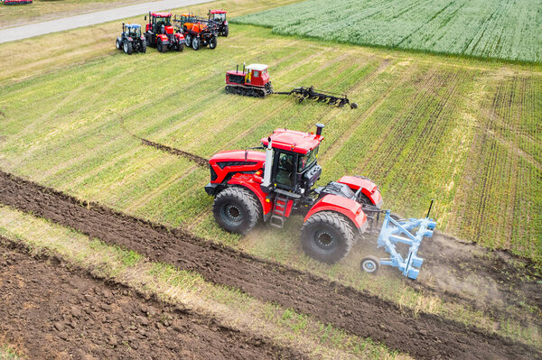 Большая сельскохозяйственная машина обрабатывает землю. Вид с вершины. Пахать землю для посадки сельскохозяйственных культур. фото с высоты птичьего полета с помощью квадрокоптера