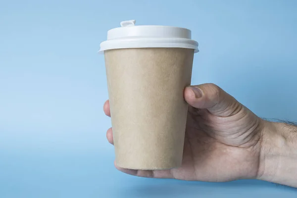 Paper cup of coffee in mans hand. Paper cup for hot drink. Idea for layout isolated on color background, flesh color, free space for text