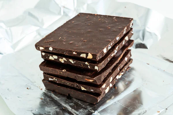Stack of chocolate slices. Hazelnut and almond milk and dark chocolate pieces tower. Sweet food photo concept. The chunks of broken chocolate