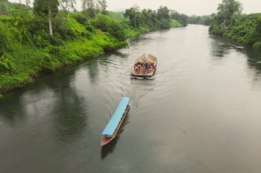 Kanchanaburi 'deki Kwai nehrinde akan şelalenin yakınındaki ahşap botu sürükleyen uzun kuyruklu teknenin üst görüntüsü. Tayland. 5 Temmuz 2023.