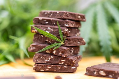CBD ve tahıl gevrekli marihuana yaprağı yenilebilir kenevir çok tahıllı çikolata, Tayland keneviri ve kahverengi ahşap arka planda yağlı kanabiler..