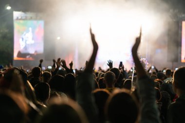 Gece kulübündeki bir konserde rock grubu çalacak. Ön sıradan bir kalabalık parti veriyormuş. Hayranların siluetleri Sahnede Parlak Renkli Çarpıcı Işıkların Önünde Ellerinizi çırpın.