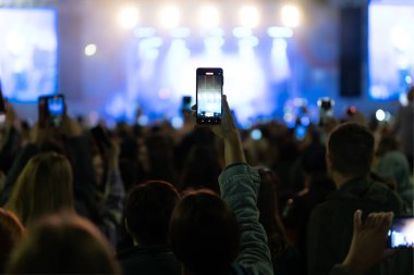 Canlı konserde fotoğraf ve video çekmek için kamera telefonu kullanan eller, canlı müzik festivalinde akıllı telefon kayıtları, konser sahnesinde fotoğraf çekmek, mutlu gençlik, lüks parti.