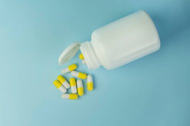 Sarı zerdeçal tedavi kapsülleri, bitkisel vitamin hapları veya tedavi için mavi arka plan, ilaç ve sağlık konsepti, kapatın, üst görünüm.
