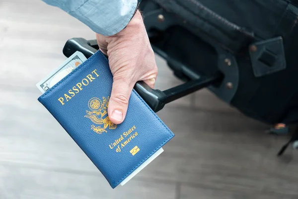 stock image a man's hand with an American passport and luggage in close-up. The concept of migration and travel. Foreign trips. Flights in the United States of America