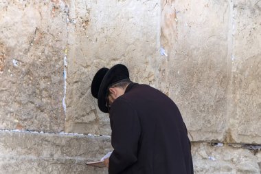 Kudüs 'teki ağlama duvarındaki Yahudi adam. Geleneksel elbiseli bir adam batı duvarının kutsal taşları önünde başını eğiyor. Dua etmek ve Tanrı 'yla kutsal dini mekanların yakınında konuşmak. Yahudilik.