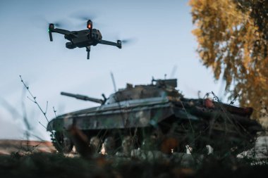 Arka planda, tankın üzerinde uçan bir dron. Modern savaşta keşif dronlarının yardımı.