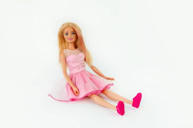 9 Ekim 2023. Barnaul, Rusya: Pembe elbiseli gevşek sarı saçlı Barbie bebek beyaz arka planda tek başına oturuyor.