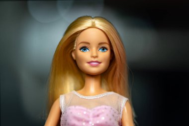 9 Ekim 2023. Barnaul, Rusya: Koyu arkaplanda pembe bir elbise içinde gevşek sarı saçlı bir Barbie bebeğin portresi.