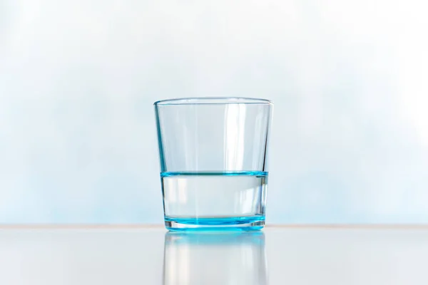 Clear and glass of water. blue glass with clear water on a blue background