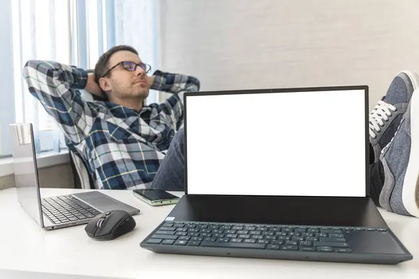 handsome man feeling bored, frustrated and sleepy after a tiresome. businessman and desk concept. copy space on an empty white laptop screen. a happy freelancer does not want to work in an office.