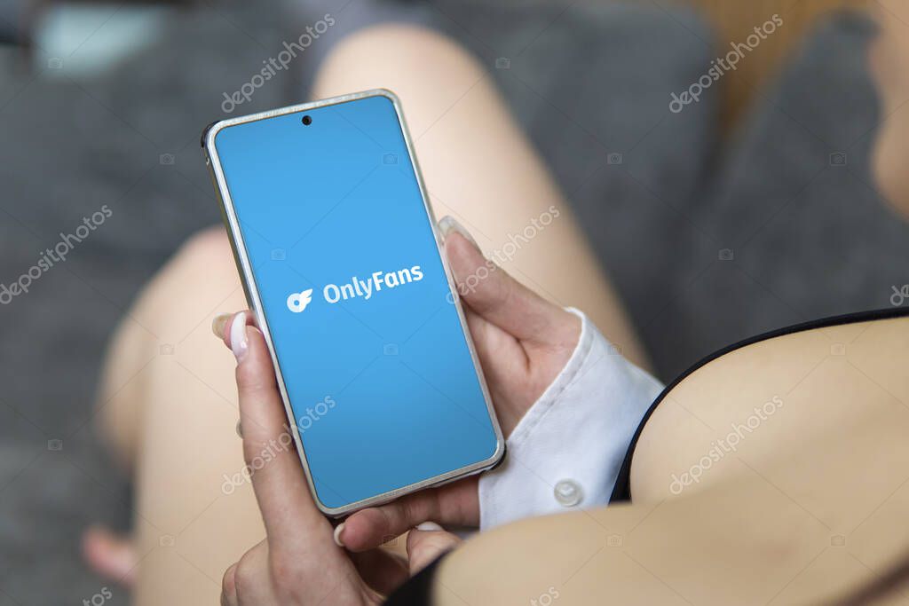 Barnaul. Russia March 28, 2023: OnlyFans logo on mobile phone in the hands of sexy women. OnlyFans is an internet paid content subscription service.