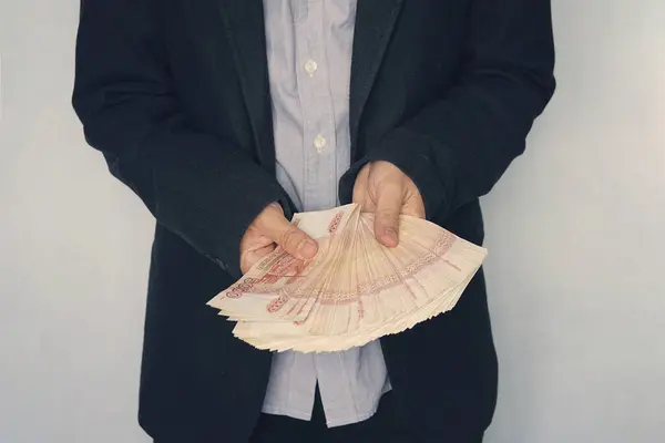Russian banknotes rubles in hand. businessman thinks of profit. Money raised from the sale of property. a large wad of money with a million rubles in the hand of a successful young man.