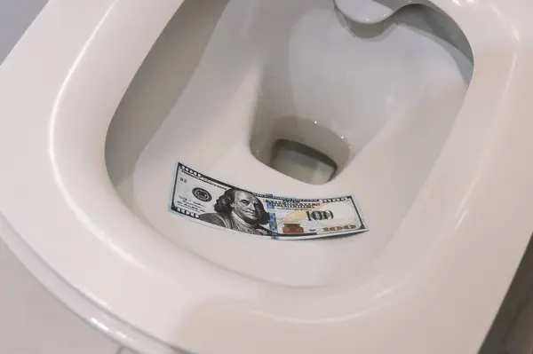 Dollars in toilet. Dollars are used instead of toilet paper, thrown down toilet and flushed down restroom. Flushing toilet. Crisis of American dollar and economy. Discarded money in sewage