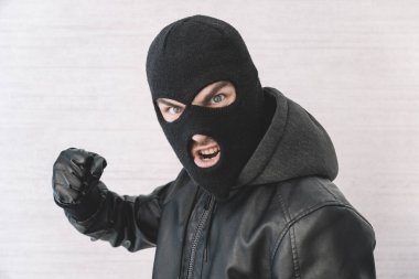 Siyah ceketli bir hırsız. Yüzünde şeytani bir ifade olan siyah kar maskeli bir adam. Beyaz arka planda saldırgan bir haydut. Suç ya da hırsızlık kavramı.