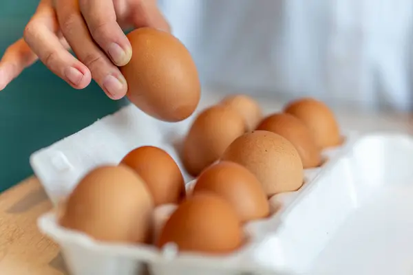 Woman\'s hand picking egg. Hand-selected egg in white paper trays container. bio-organic produce, eco food concept.