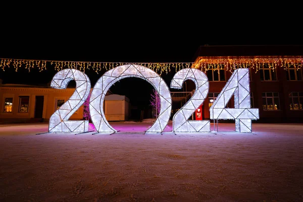 2024 figures on snow on a dark night background. Decorative figures decorate the city square for the celebration of the new year.