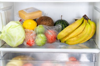 Taze meyve ve sebzelerle dolu açık bir buzdolabı, sağlıklı gıda geçmişi, organik beslenme, sağlık hizmetleri, diyet konsepti. Buzdolabının rafında taze sebzeler var..