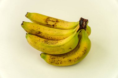 Olgun sarı muzlu meyveler, beyaz arka planda koyu benekli olgun muzlar.