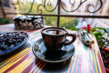 Masadaki siyah kupa, ortaçağ mimarisinin arka planına karşı. Özbek tarzı fincanda sade kahve.