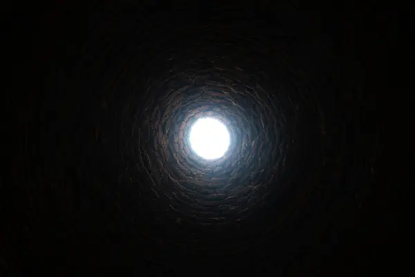 The old deep abandoned well. Inside view. The light at the end of the tunnel concept