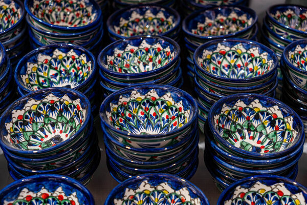 Bukhara. Uzbekistan. Shopping place. Ceramic cups and bowls decorated by traditional uzbek patterns. Blue pattern. lots of cups of blue color on the background. Ceramic craft of modern Uzbekistan.