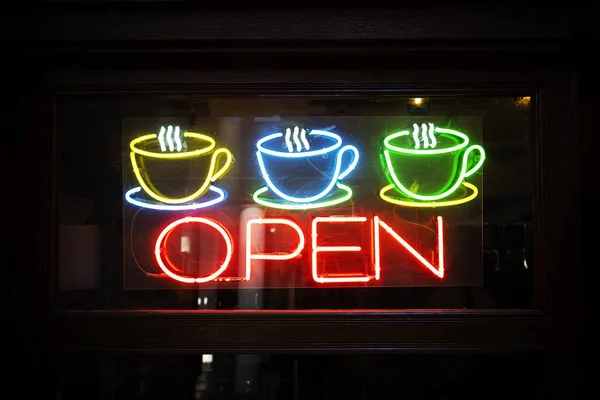Neon open sign with coffee cup on glass door. an open cafe.