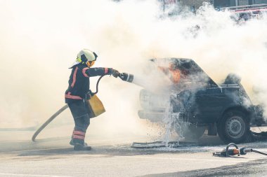 Yangın söndürücü yanan bir arabayı yangın hortumu, yangın ve otomatikten söndürür. Bir itfaiyeci yangın söndürücüyle bir arabayı söndürüyor..