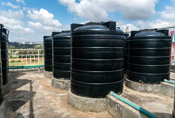city roofs are occupied by black water storage tanks. Water tank on roof in Africa. Water heating tank against sea and the city. Asian water supply and heating system