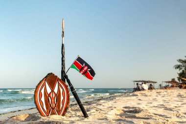 Masai 'nin mızrağı ve Kenya' nın ulusal bayrağı güzel bir sahil manzarasının arka planında. Afrika turizmi kavramı.