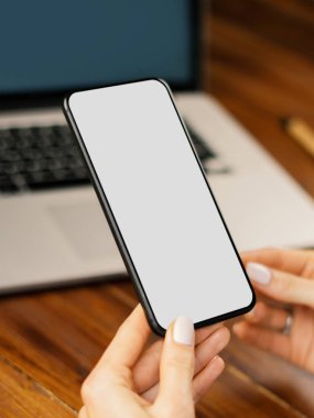 Ahşap masada boş ekranlı akıllı telefon kullanan bir kadının görüntüsü. Kadın eli ve cep telefonunun yakın fotoğrafını çek