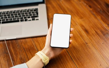 Ahşap masada boş ekranlı akıllı telefon kullanan bir kadının görüntüsü. Kadın eli ve cep telefonunun yakın fotoğrafını çek