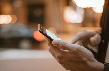 Açık havada, Night City Caddesi 'nde akıllı telefonları olan erkeklerin yakın çekimleri.