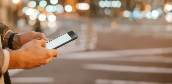 Açık havada, Night City Caddesi 'nde akıllı telefonları olan erkeklerin yakın çekimleri.
